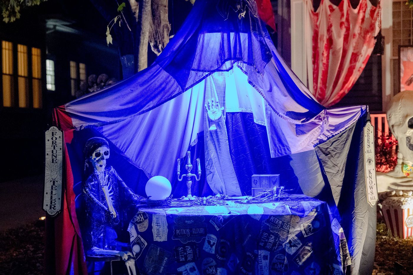 Halloween fortune teller setup with skeletons and eerie lighting outside a home.