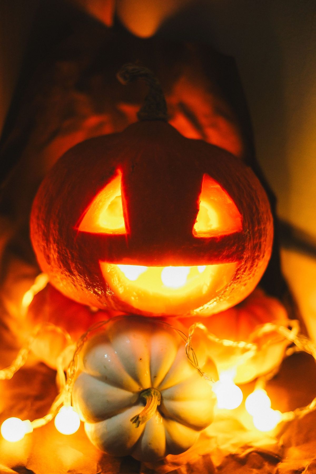 Illuminated carved pumpkin with candlelight and string lights, perfect for Halloween ambiance.