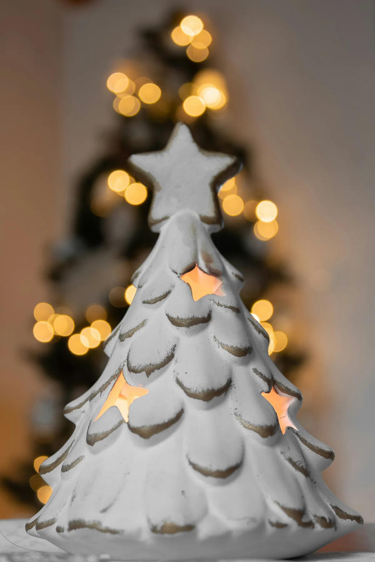 Little tree with candle inside with christmas tree in the background
