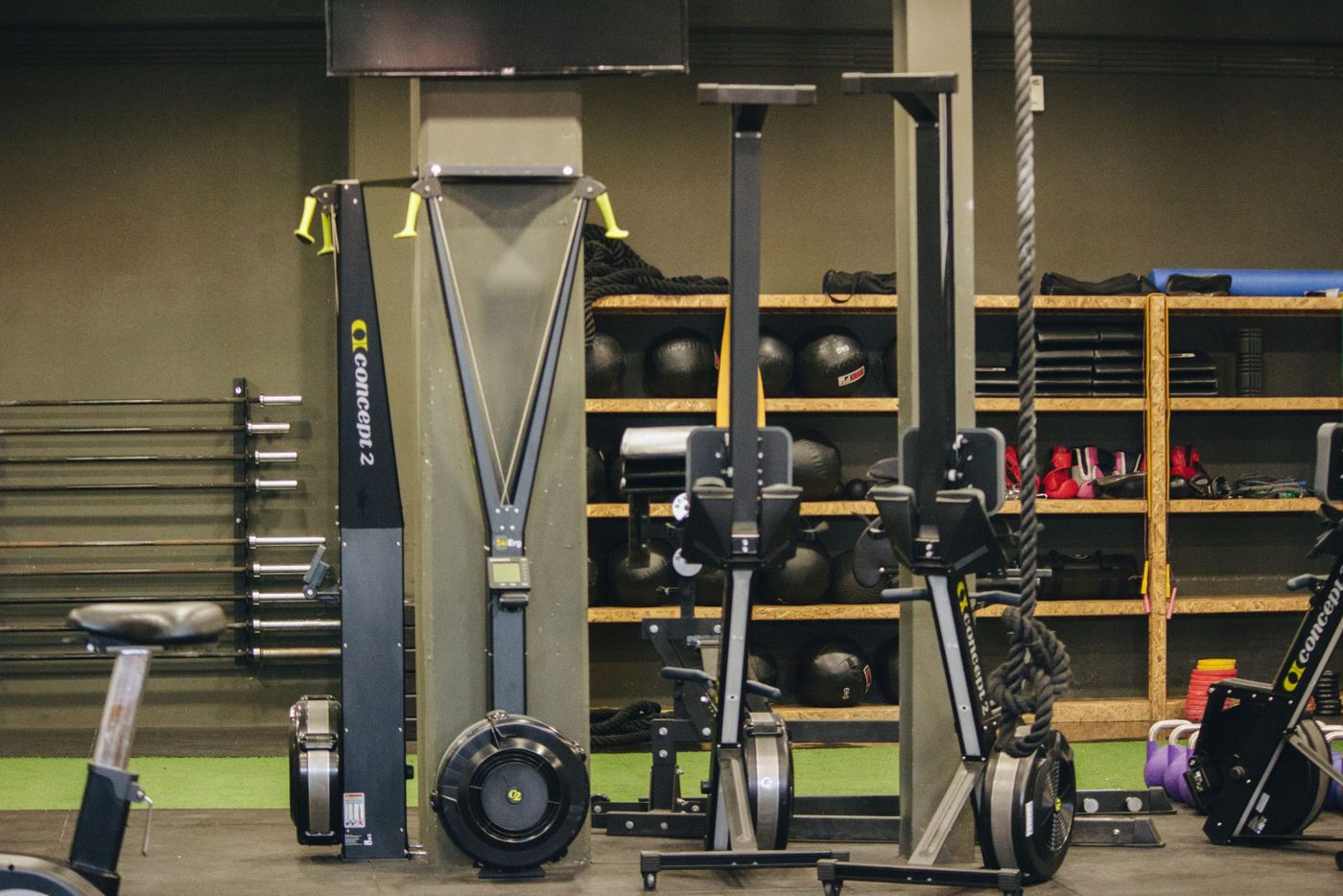Modern gym with exercise equipment including rowing and ski machines, weights, and ropes.