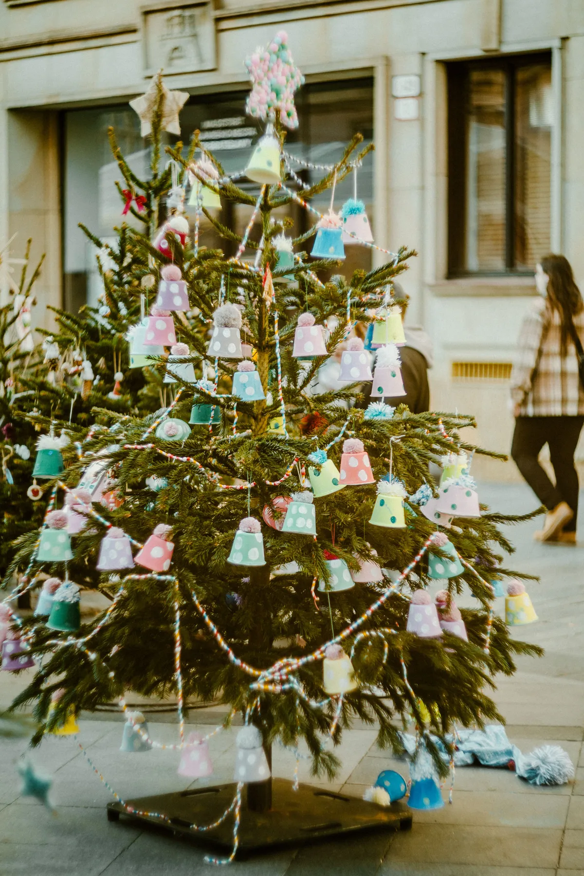 Outdoor Christmas tree adorned with vibrant bell decorations in urban setting