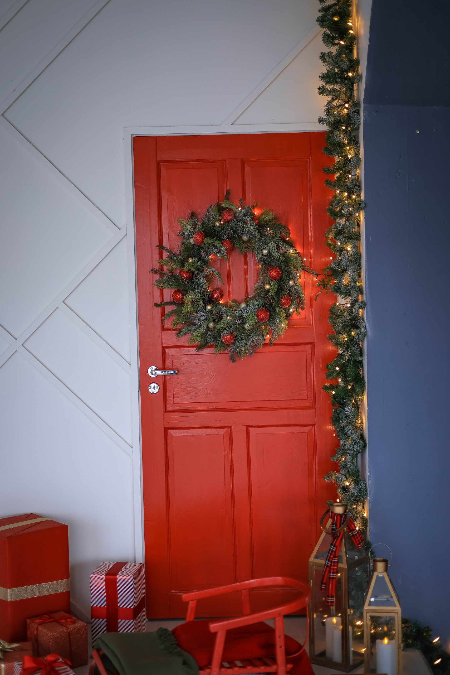 Red door adorned with festive wreath and lights, perfect for holiday ambiance.