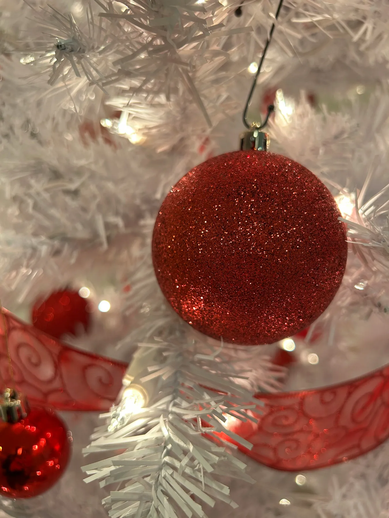 Red ornaments on a white christmas tree