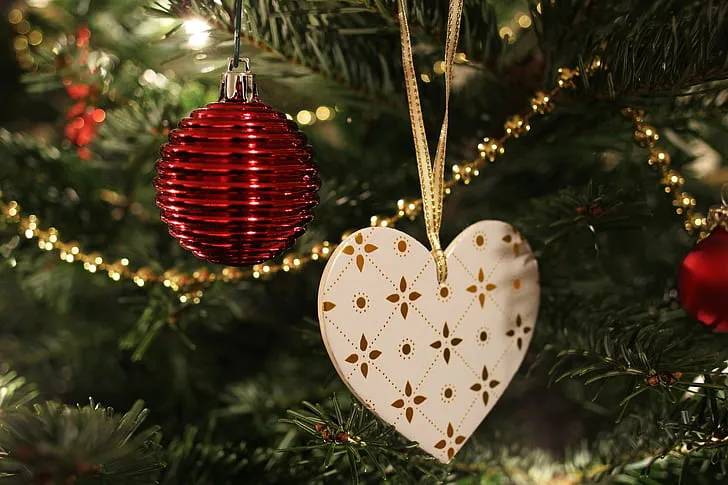 Royalty-Free photo: Red bauble and white heart ornament hanged on green Christmas tree | PickPik
