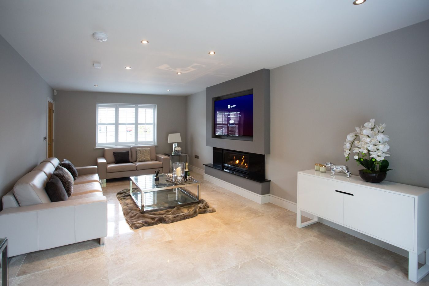 Spacious and elegant modern living room featuring a cozy fireplace and stylish decor.