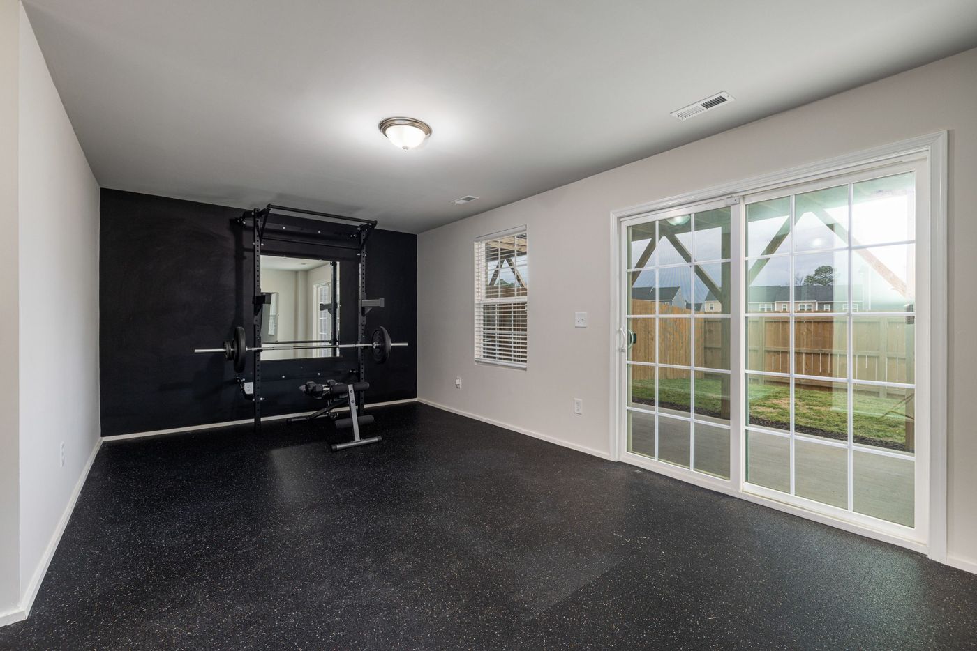 Spacious home gym featuring weightlifting equipment and a mirrored wall.