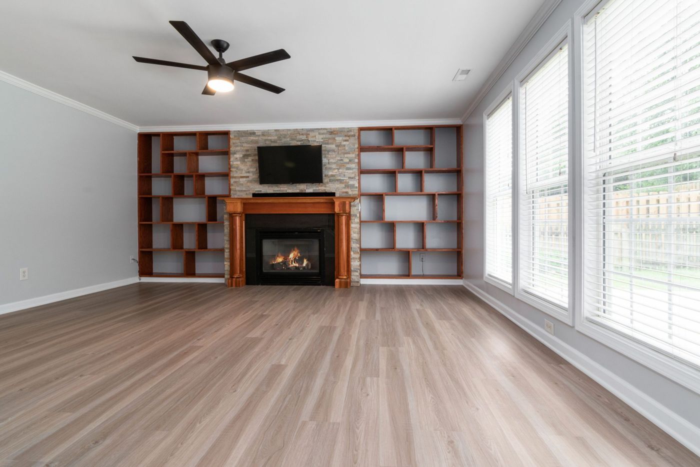 Spacious living room featuring a fireplace, built-in shelving, and large windows.