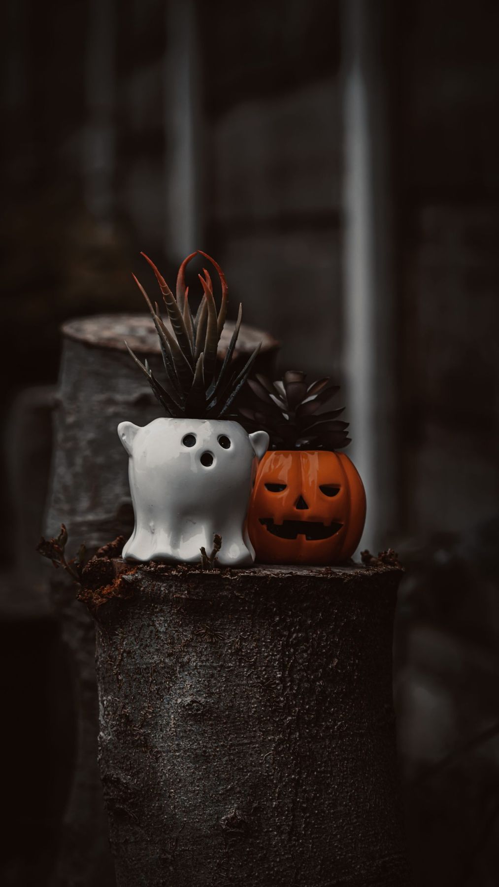 Spooky Halloween decor with ghost and pumpkin planters in a moody setting.