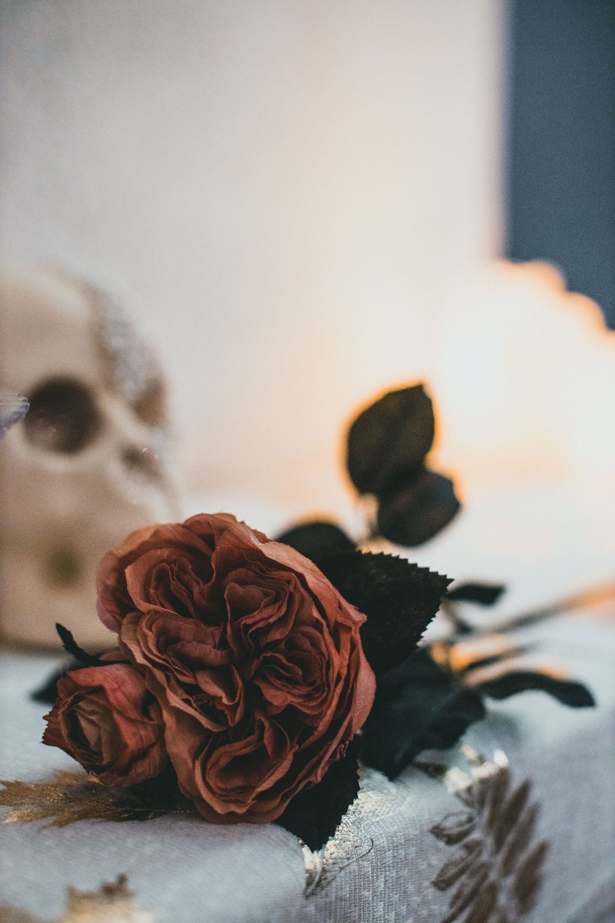 Spooky Halloween floral arrangement with roses and skull on a table, indoors.