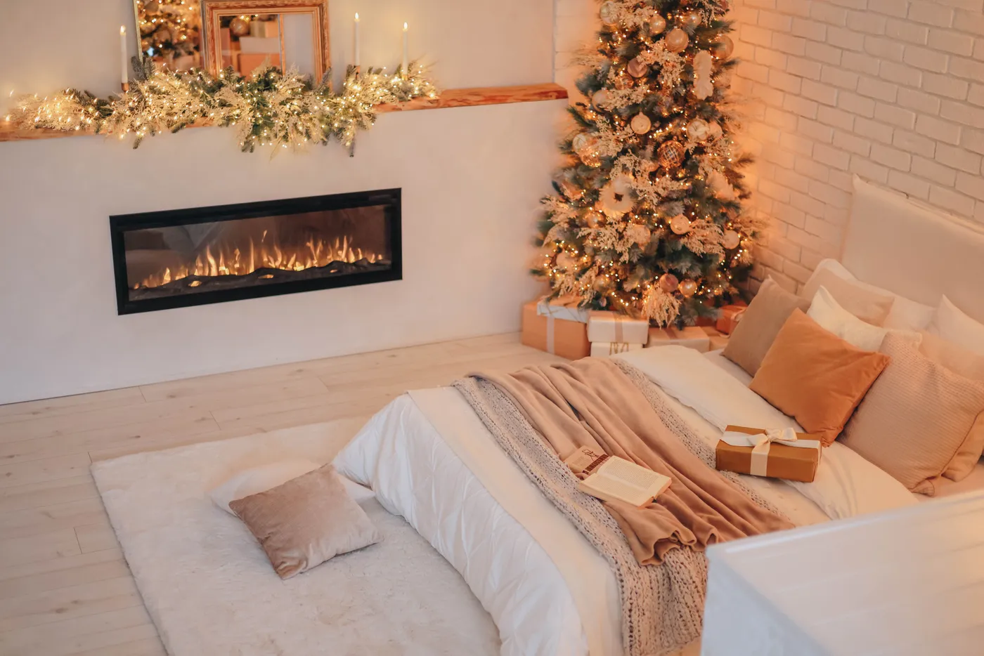 Warm and inviting Christmas-themed bedroom with a fireplace and decorated tree.